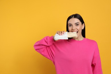 Photo of Young woman eating delicious shawarma on yellow background