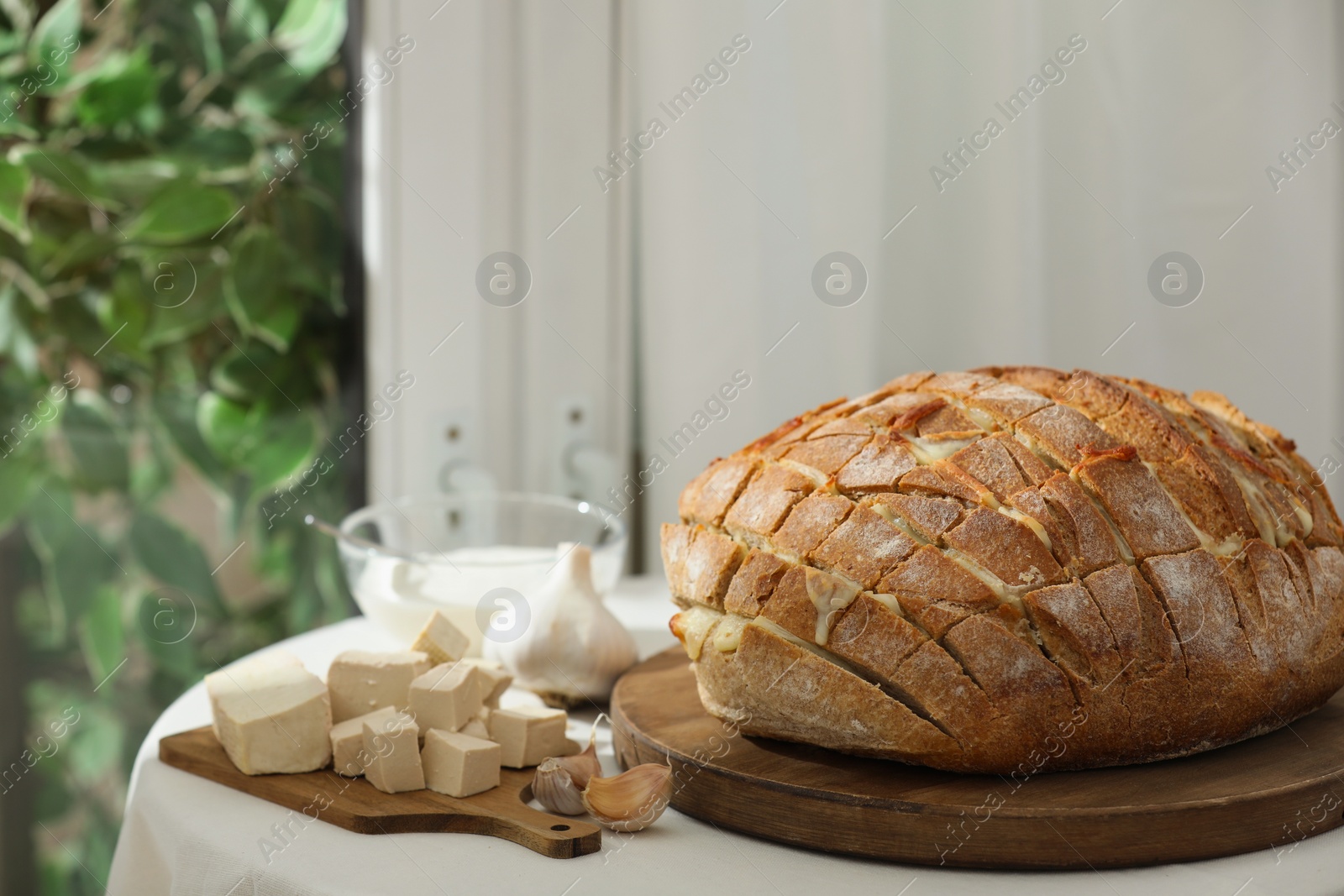 Photo of Freshly baked bread with tofu cheese and ingredients on table indoors