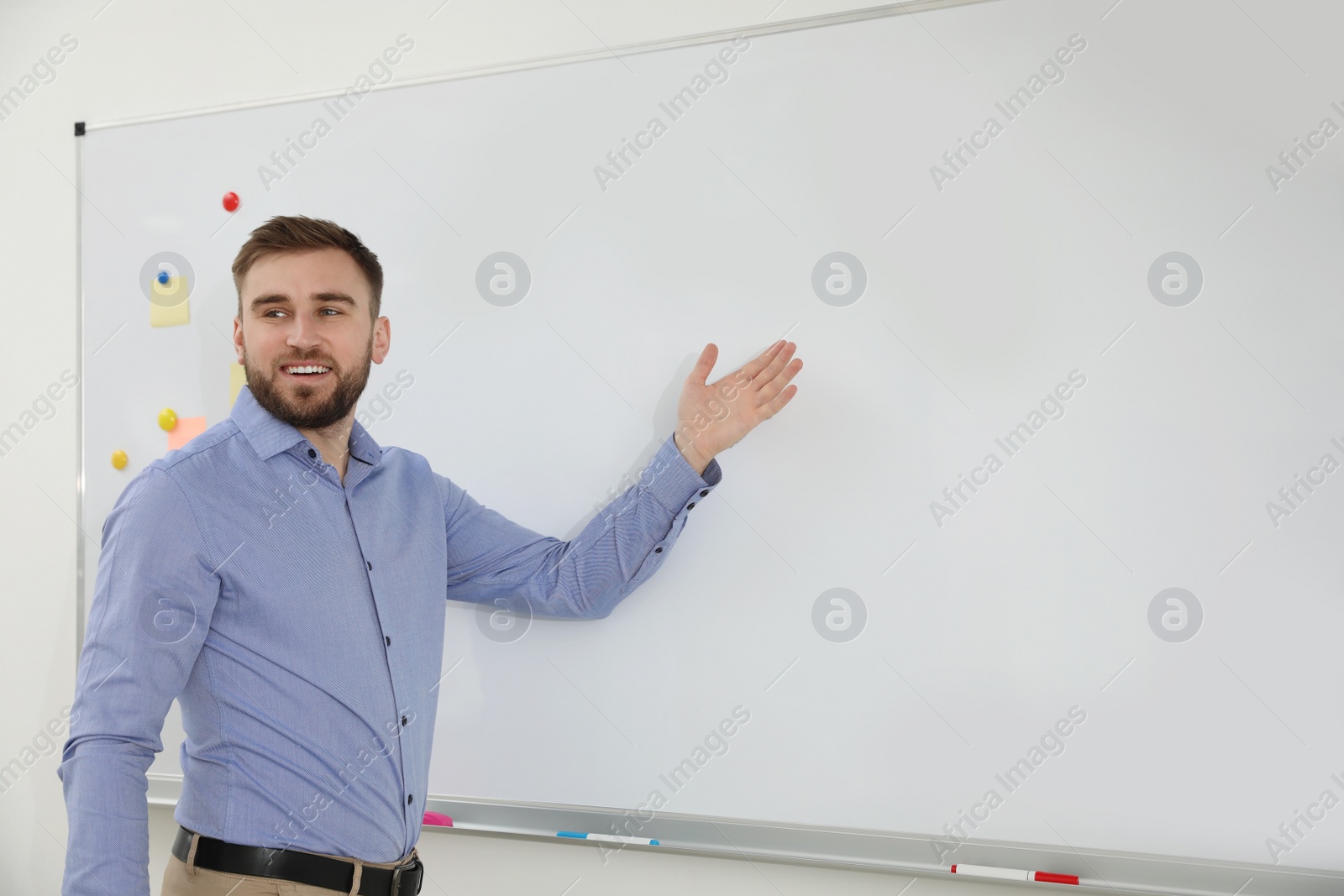 Photo of Portrait of young teacher near whiteboard in classroom. Space for text