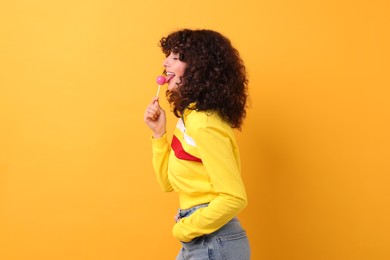 Beautiful woman with lollipop on yellow background