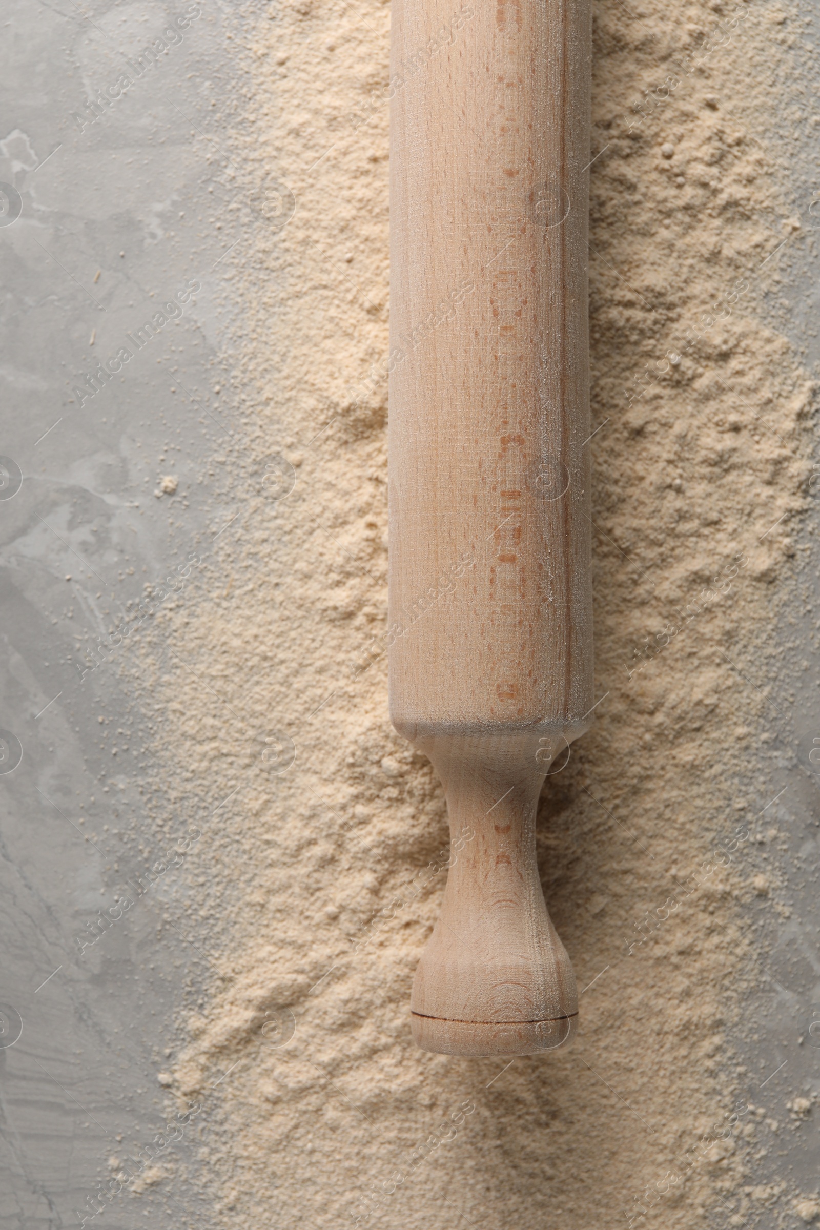 Photo of Flour and rolling pin on grey marble table, top view