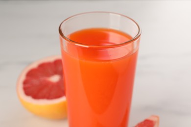 Tasty grapefruit juice in glass and fresh fruit on white table, closeup