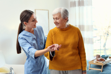Photo of Care worker helping elderly woman to walk in geriatric hospice