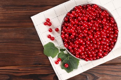 Photo of Ripe red currants and leaves on wooden table, flat lay. Space for text