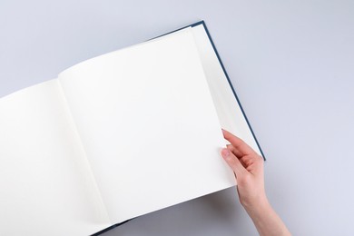 Woman with open photo album at light table, top view. Space for text