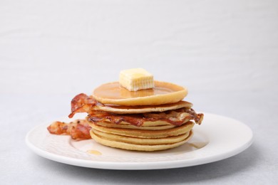 Photo of Delicious pancakes with bacon, butter and honey on light table, closeup