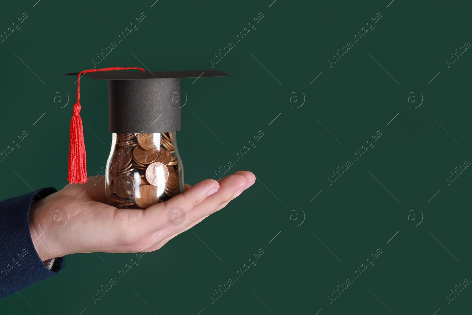 Photo of Man holding glass jar of coins and graduation cap against green background, closeup with space for text. Scholarship concept