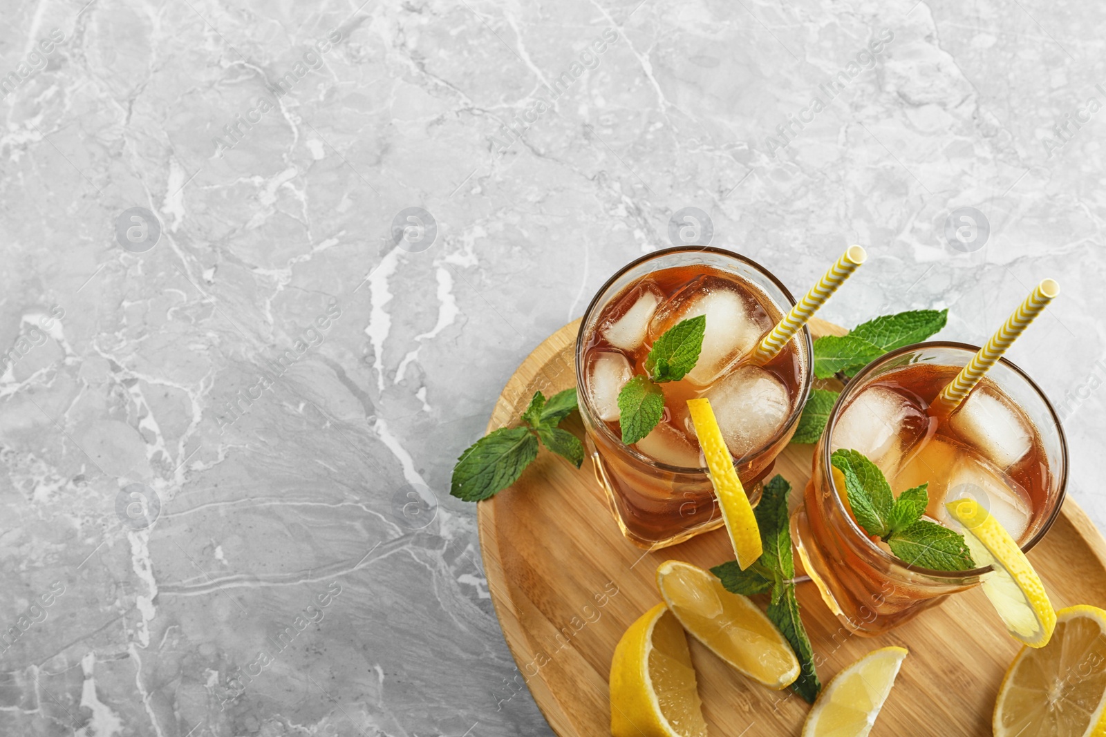 Photo of Glasses of delicious iced tea on marble table, top view. Space for text