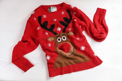 Christmas sweater with pattern on wooden background, top view