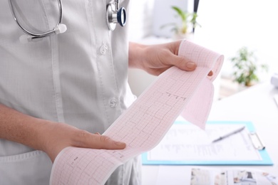 Doctor examining cardiogram in medical clinic, closeup