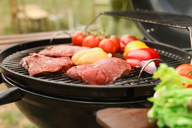 Photo of Modern grill with meat and vegetables outdoors, closeup