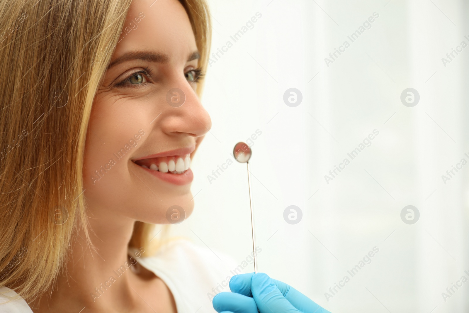 Photo of Doctor examining patient's teeth on light background, closeup. Cosmetic dentistry