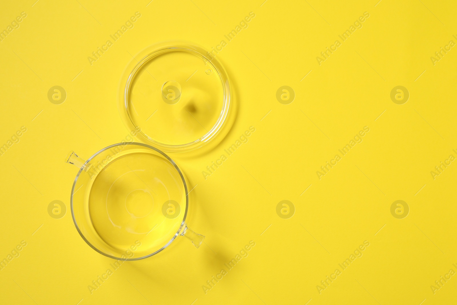 Photo of Empty glass pot and lid on yellow background, flat lay. Space for text