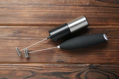 Black milk frother wands on wooden table, top view