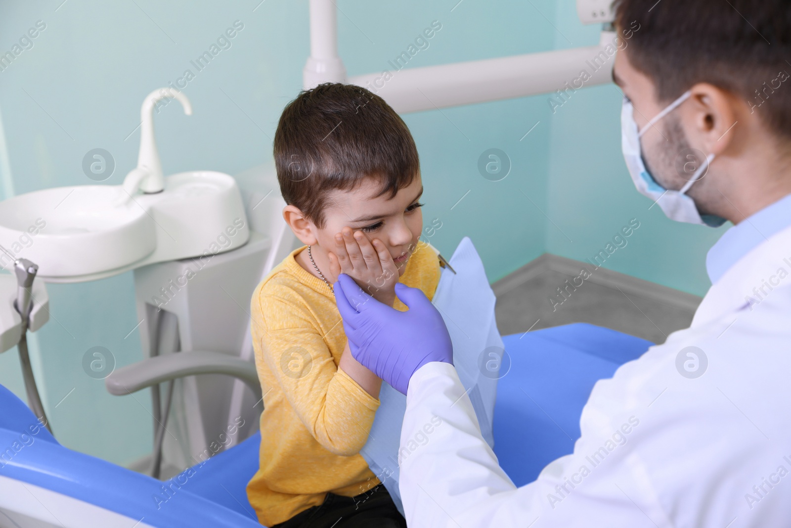 Photo of Professional dentist working with little patient in modern clinic