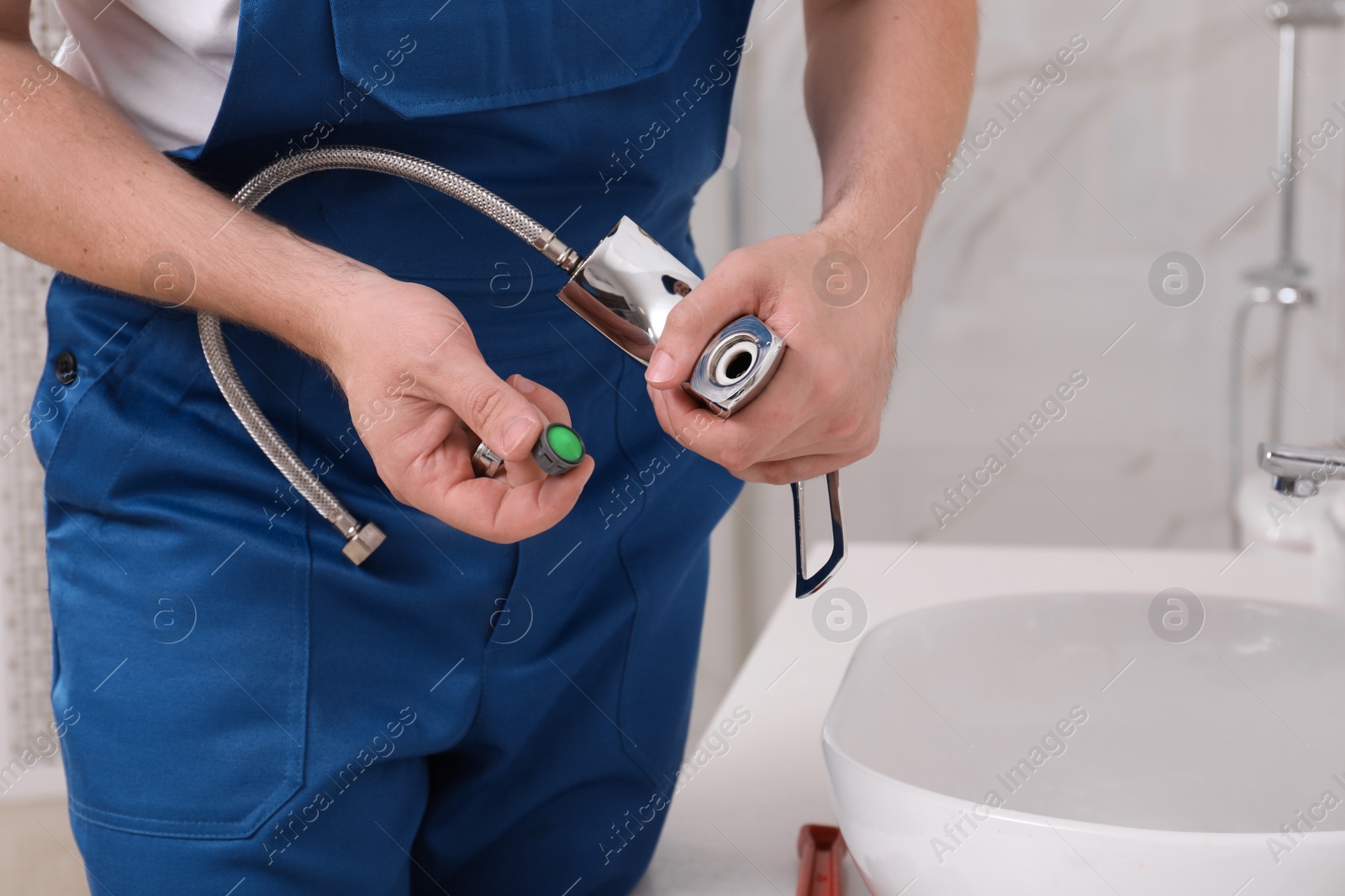 Photo of Professional plumber fixing water tap in bathroom, closeup