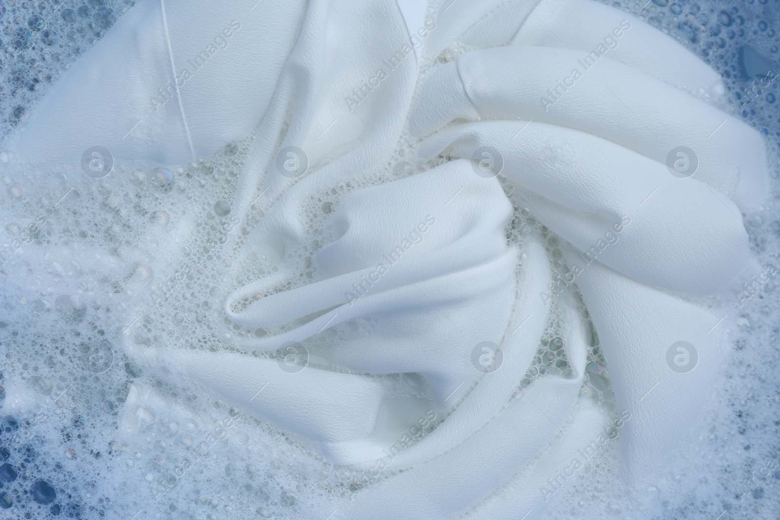 Photo of White clothing in suds, top view. Hand washing laundry