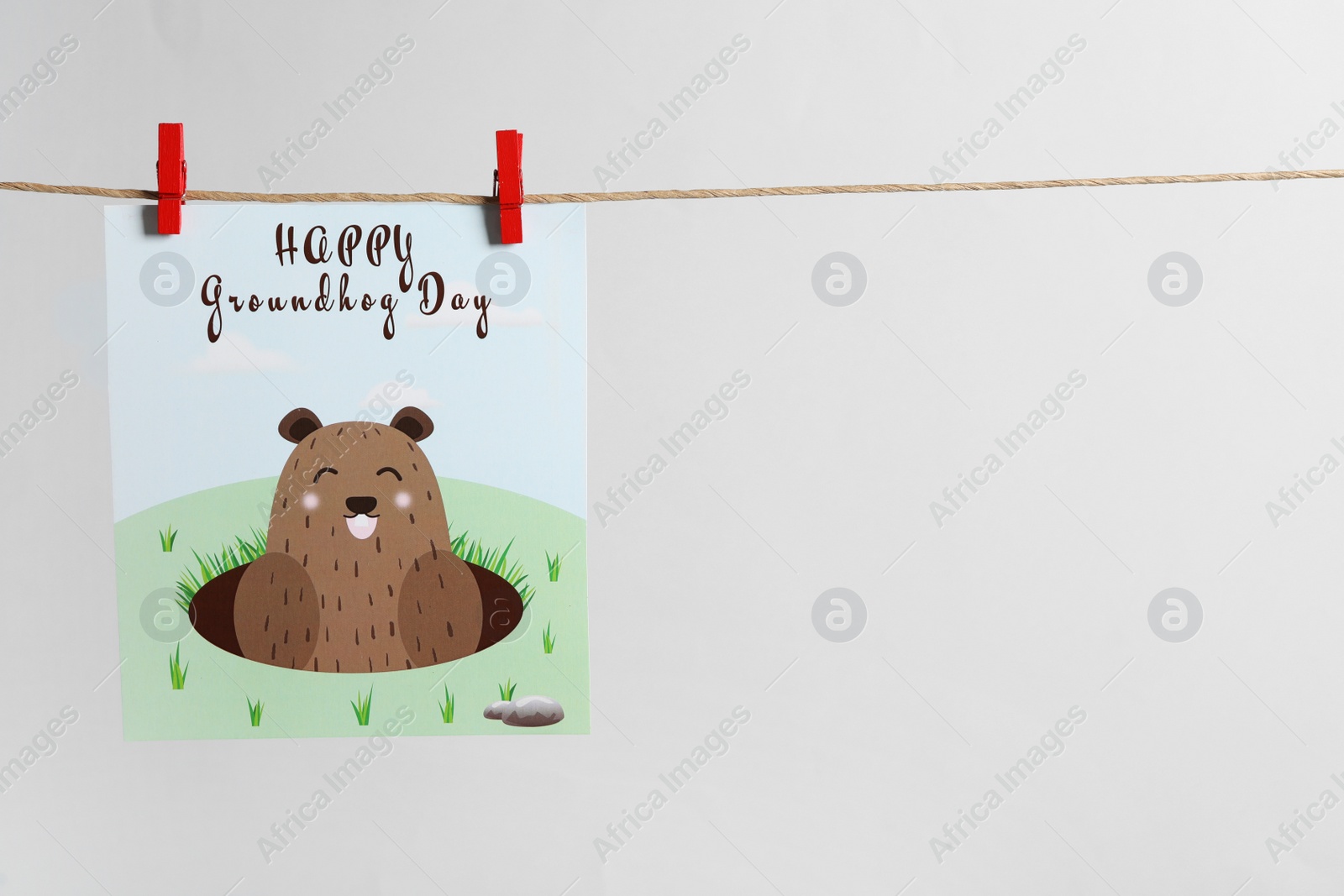 Photo of Happy Groundhog Day greeting card hanging on light background, space for text