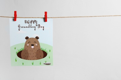 Photo of Happy Groundhog Day greeting card hanging on light background, space for text