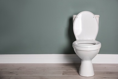 Photo of New ceramic toilet bowl near grey wall