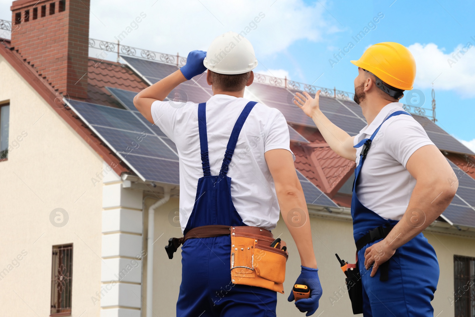 Image of Engineers near house with solar panels. Alternative energy source