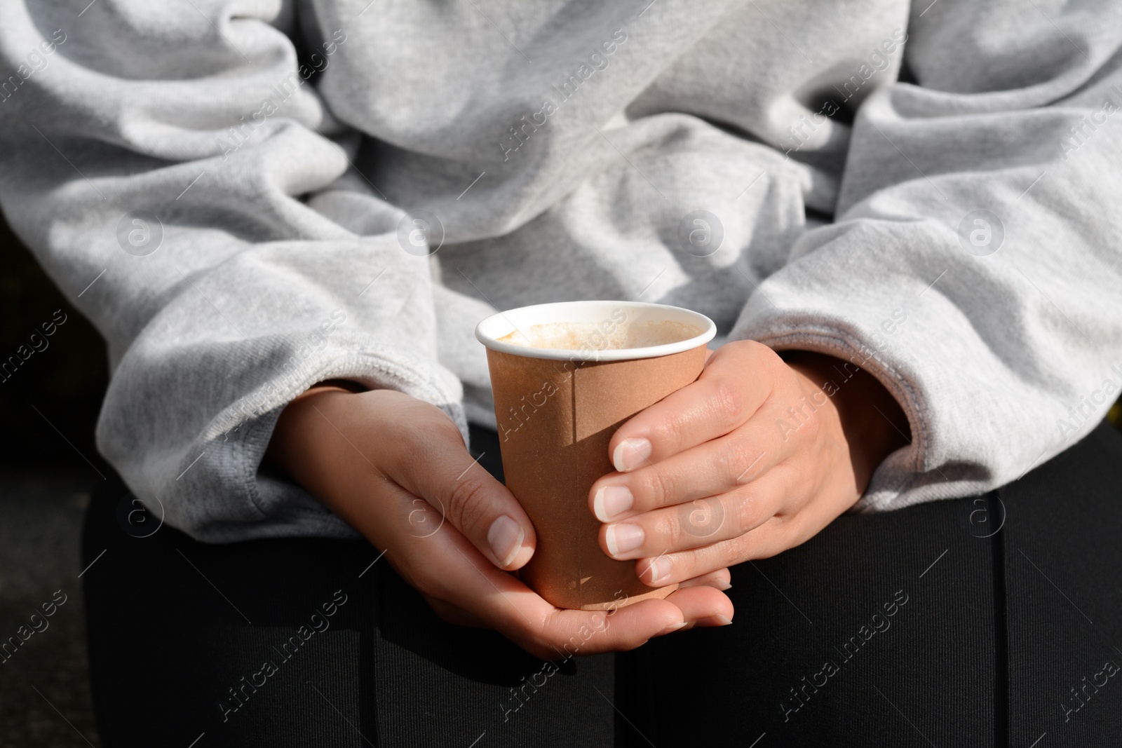 Photo of Woman sitting with cardboard cup of coffee, closeup