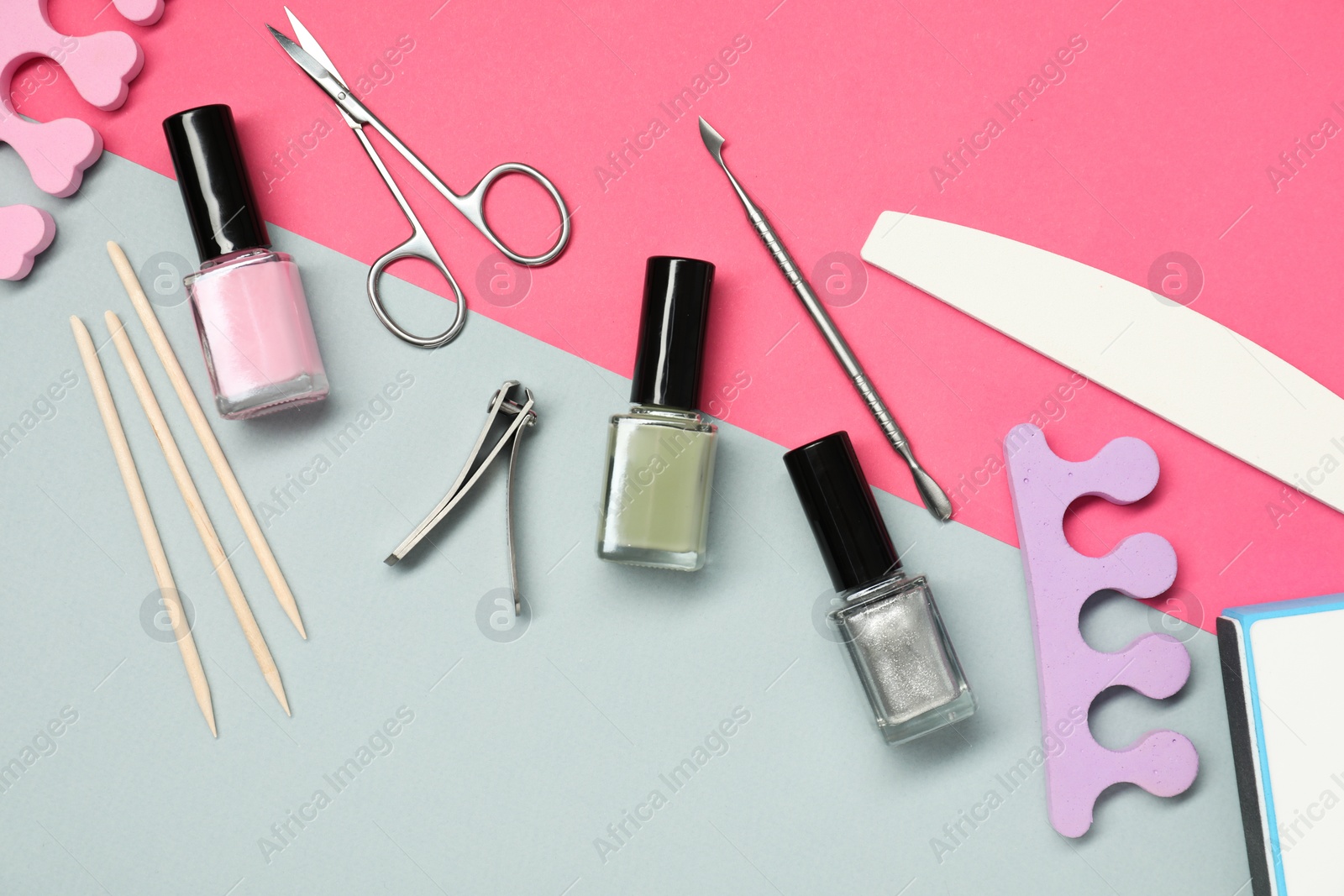 Photo of Nail polishes and set of pedicure tools on color background, flat lay