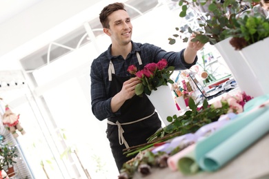 Photo of Male florist creating beautiful bouquet in flower shop