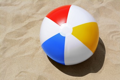 Photo of Colorful beach ball on sand, top view