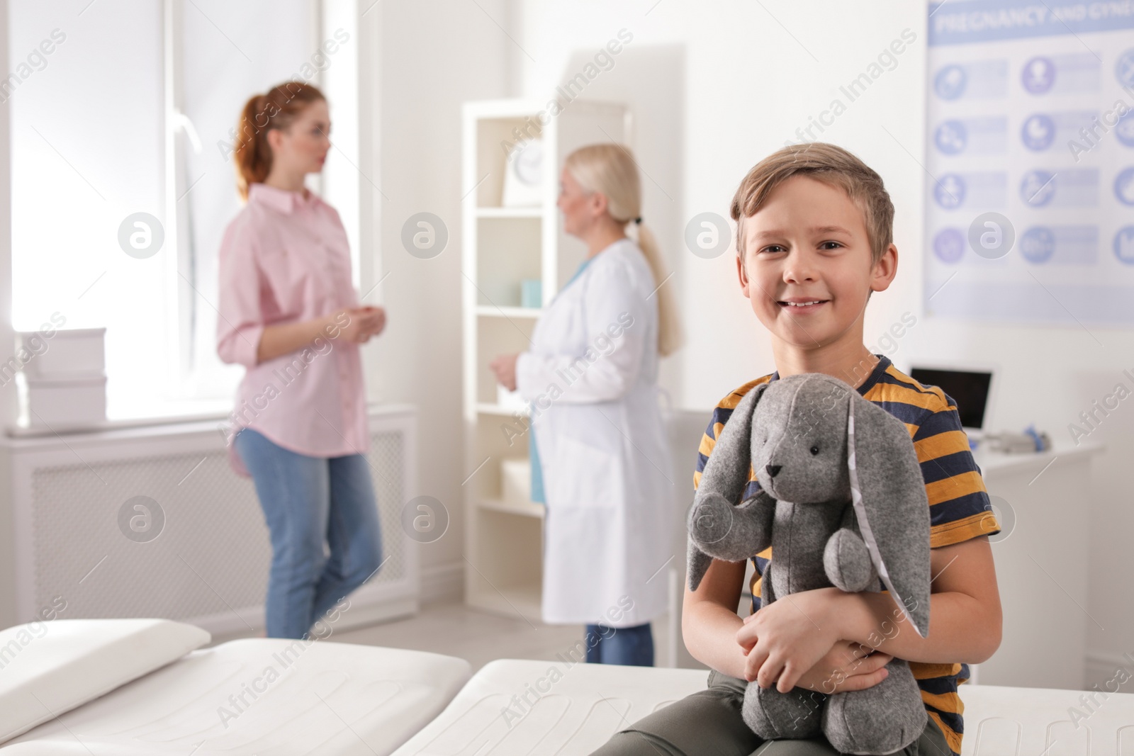 Photo of Adorable child with toy and mother visiting doctor at hospital