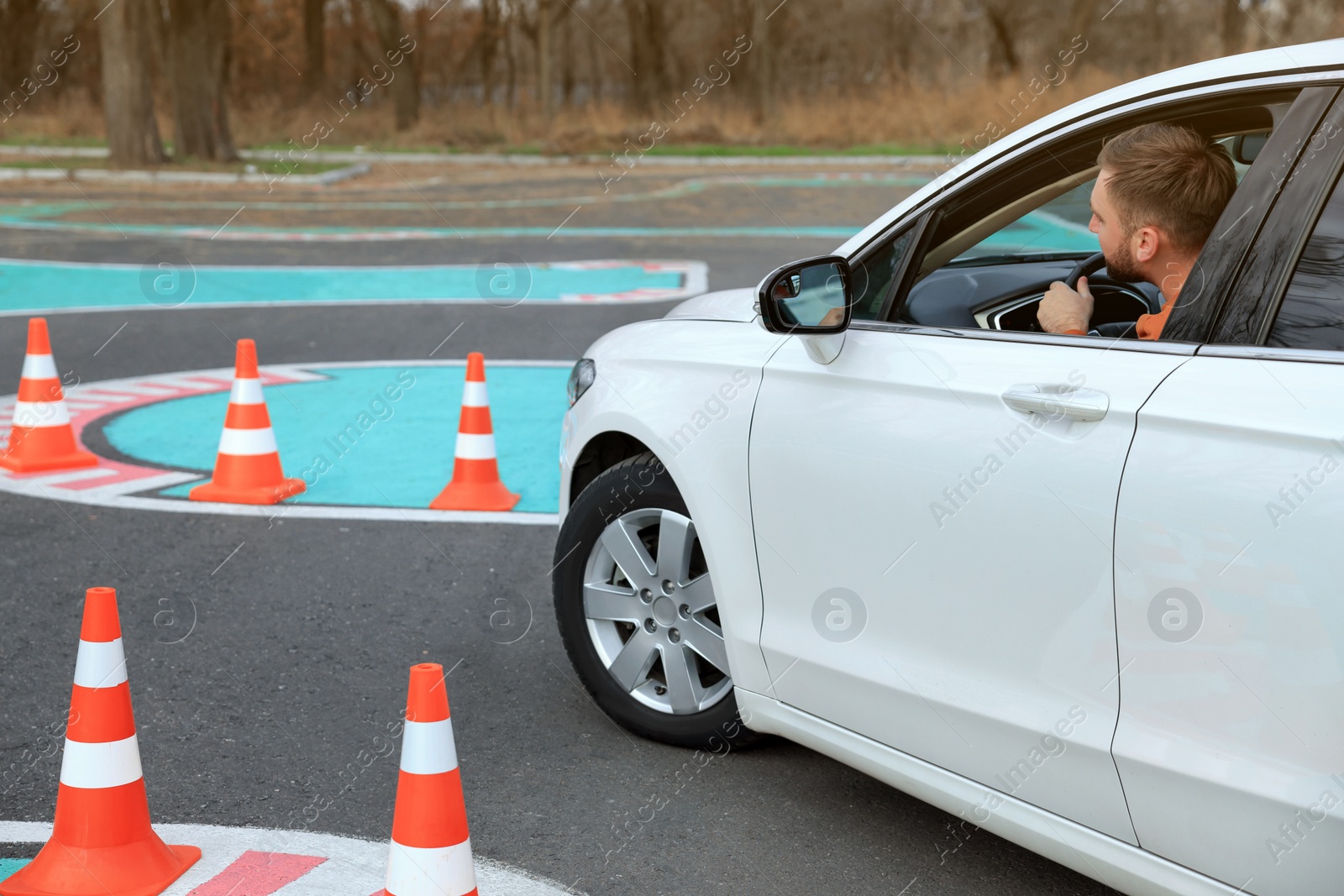 Photo of Young man in car on test track with traffic cones. Driving school