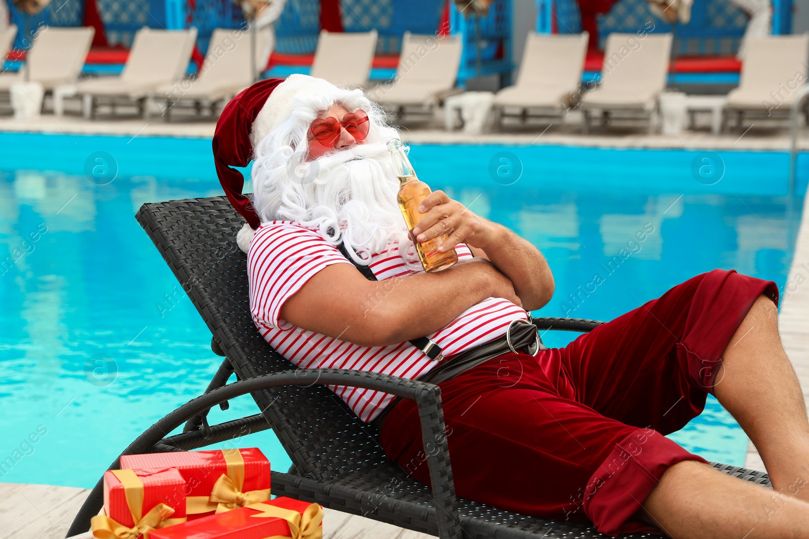 Photo of Authentic Santa Claus with bottle of beer near pool at resort