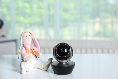 Photo of Baby camera with toy on table in room, space for text. Video nanny