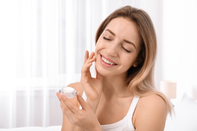 Portrait of young woman with jar of cream indoors. Beauty and body care