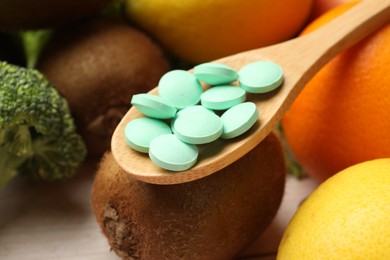 Photo of Dietary supplements. Spoon with pills near food products, closeup