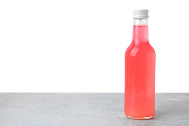 Photo of Delicious kombucha in glass bottle on grey table against white background, space for text