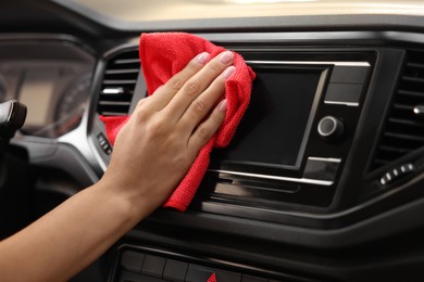 Photo of Woman cleaning center console with rag in car, closeup