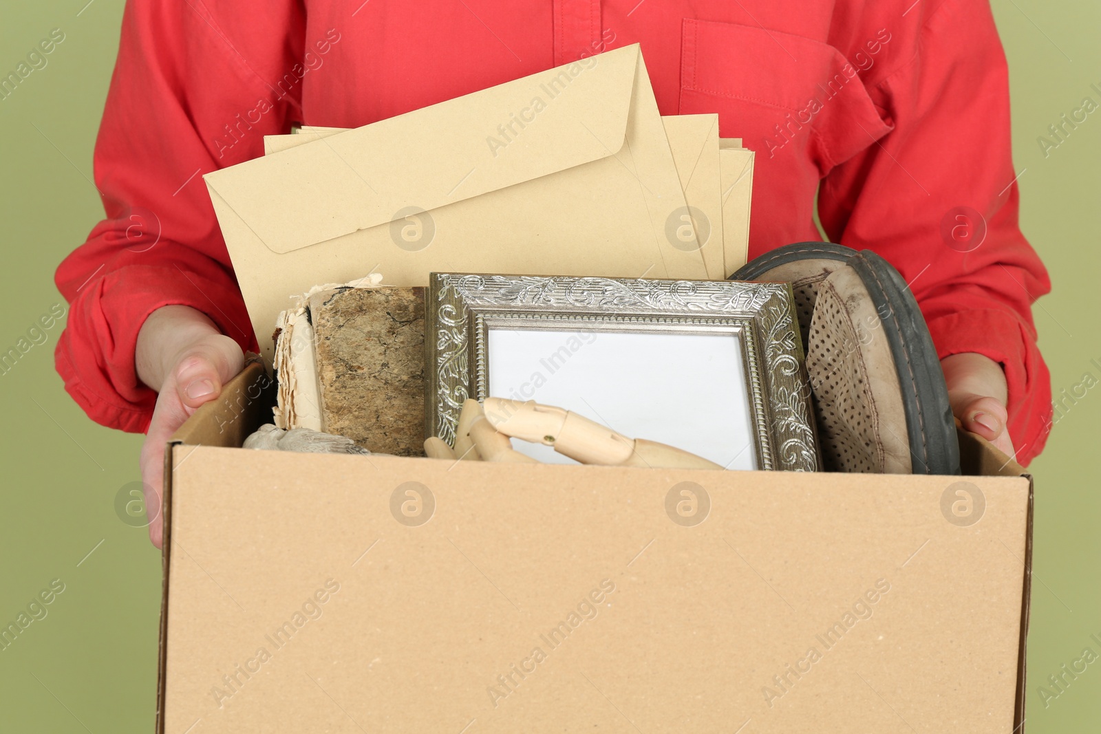 Photo of Woman holding box of unwanted stuff on green background, closeup