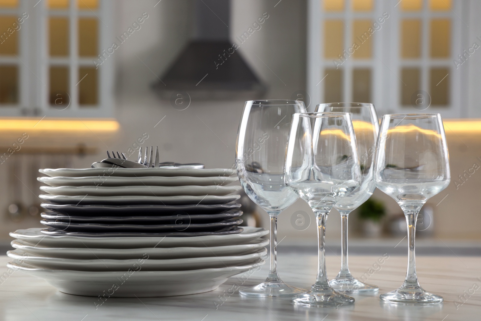 Photo of Different clean dishware, cutlery and glasses on white marble table in kitchen