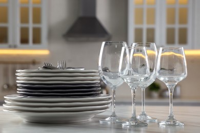 Photo of Different clean dishware, cutlery and glasses on white marble table in kitchen