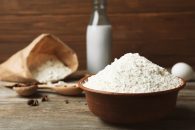 Photo of Bowl with flour on wooden table