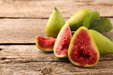 Cut and whole green figs on wooden table, closeup. Space for text