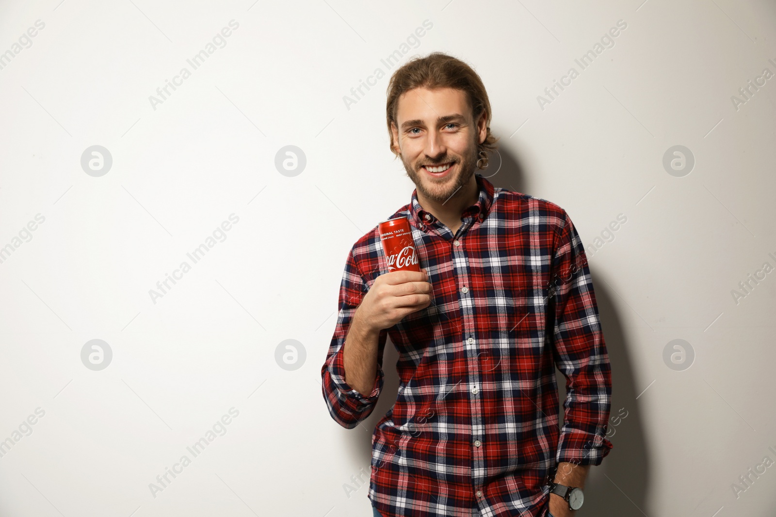 Photo of MYKOLAIV, UKRAINE - NOVEMBER 28, 2018: Young man with Coca-Cola can on white background, space for text