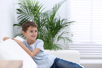 Photo of Cute little boy sitting in living room