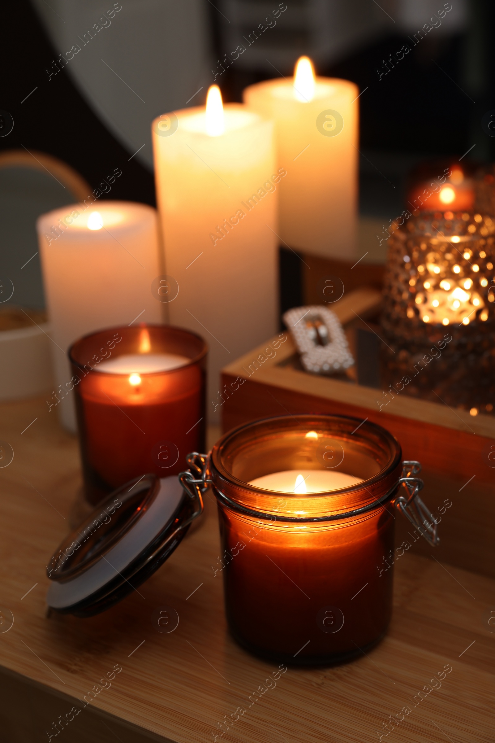 Photo of Lit candles on wooden dressing table indoors