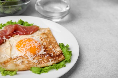 Delicious crepe with egg on light gray table, closeup. Breton galette