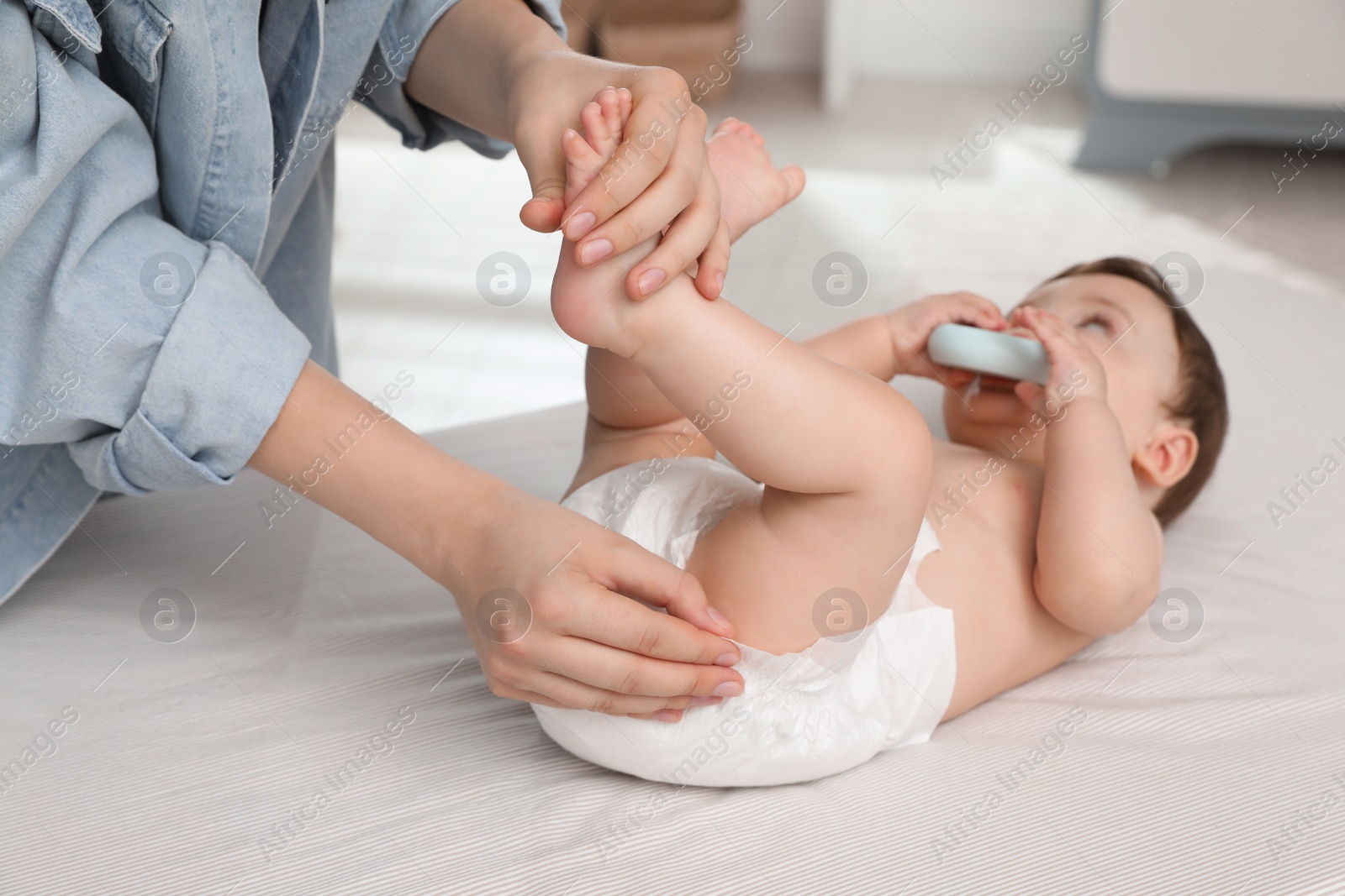 Photo of Mother changing baby's diaper on bed at home, closeup