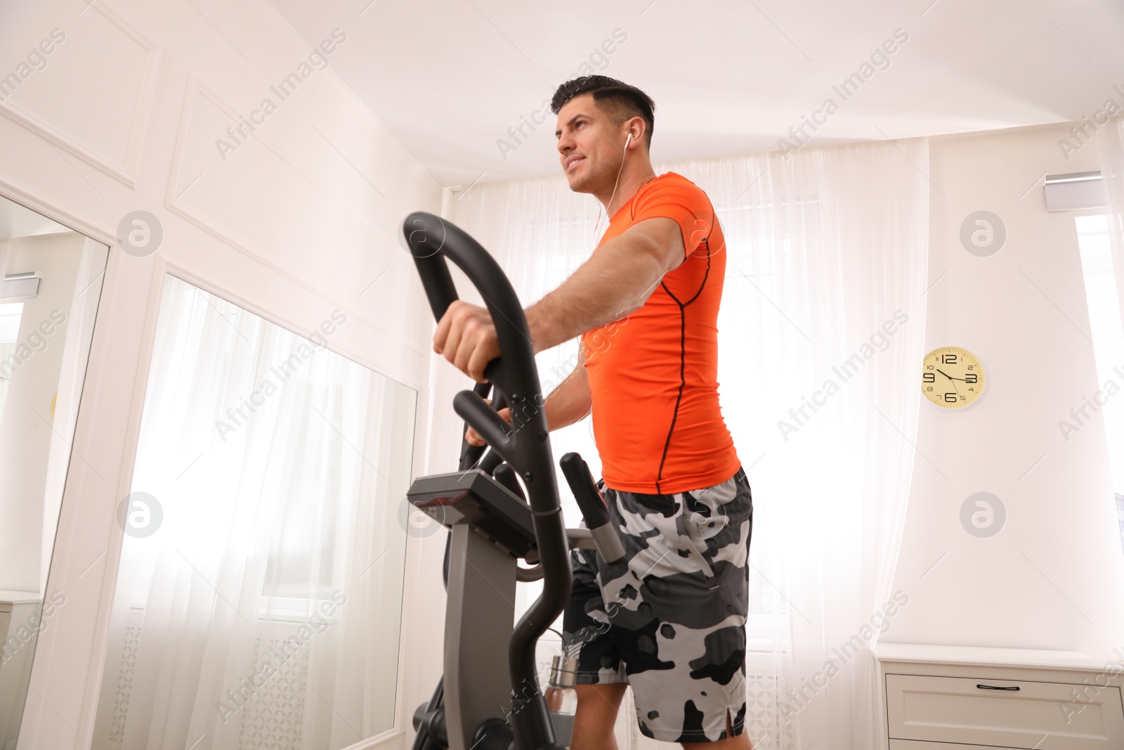 Photo of Man using modern elliptical machine at home