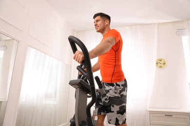 Man using modern elliptical machine at home