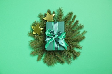 Photo of Gift box and fir tree branches on green background, flat lay